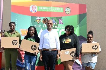 Chairman Oliver G. Gilbert standing with high school students holding laptops