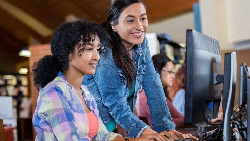 Student and tutor working on a computer.