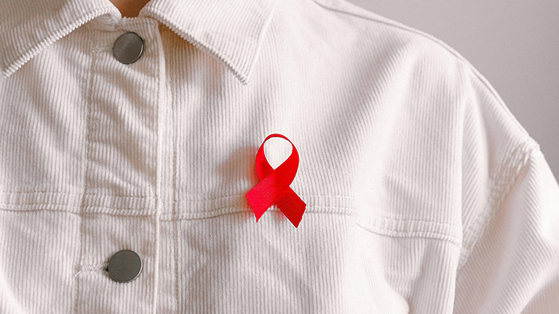 A person wearing a red ribbon on shirt